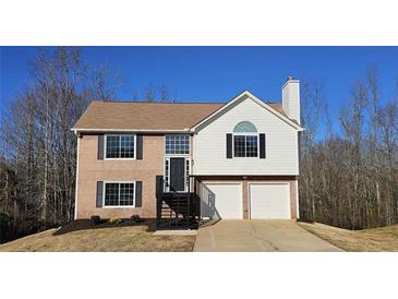 Two-story house with brick and vinyl siding, two-car garage, and a landscaped yard at 256 Kings Cv, Locust Grove, GA 30248