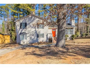 Charming two-story home with vinyl siding and a bright orange front door surrounded by mature trees at 4547 Doral Sw Dr, Atlanta, GA 30331