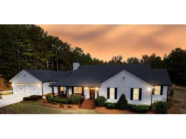 Stunning white farmhouse with black trim, large windows, and a three-car garage at 5601 Atlanta Hwy, Rutledge, GA 30663