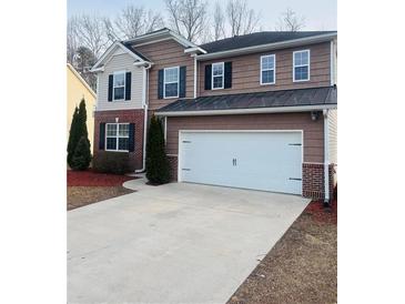 Two-story home with brown siding, a two-car garage, and well-maintained landscaping at 1963 White Top Rd., Lawrenceville, GA 30045