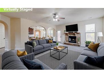Inviting living room featuring a cozy fireplace, ceiling fan, and plenty of comfortable seating at 3535 Clarecastle Dr, Buford, GA 30519
