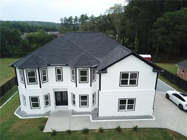 Two-story house with a black roof, white siding, and a large driveway at 7540 Union Grove Rd, Lithonia, GA 30058