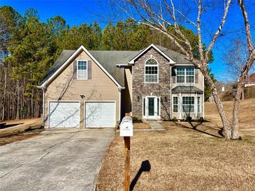 Two-story house with stone and siding accents, two-car garage, and a landscaped yard at 3877 Oakman Pl, Fairburn, GA 30213