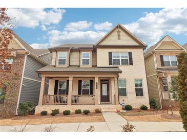 Two-story house with light beige brick and brown accents, front porch, and landscaping at 3538 Diplomat Aly, Scottdale, GA 30079