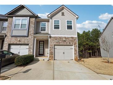 Two-story townhome with stone and shingle exterior, two-car garage, and landscaped yard at 1000 Belfry Ter, Fairburn, GA 30213