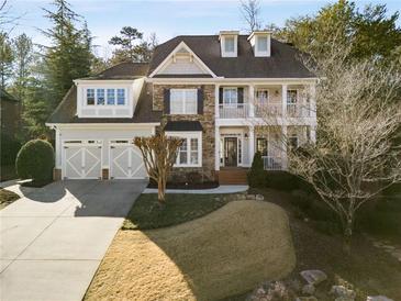 Two-story house with stone accents, a three-car garage, and a landscaped lawn at 6229 Grand Loop Rd, Sugar Hill, GA 30518