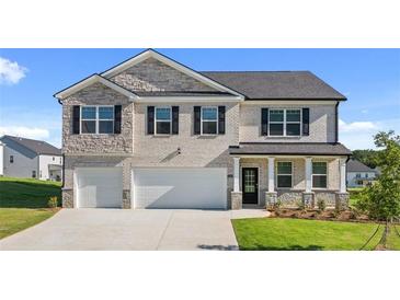 Two-story house with gray stone and white accents, two-car garage, and landscaped lawn at 3238 Champions Way, Loganville, GA 30052