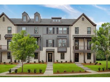 Brick and gray-sided townhome with front yard landscaping, walkway, and attached balcony at 315 Enchanted Ct, Fayetteville, GA 30214