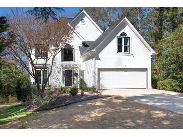 Charming two-story home with white exterior, arched windows, manicured lawn, and two car garage at 4086 Haverhill Dr, Atlanta, GA 30342