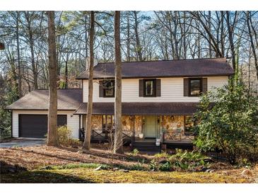 Charming two-story home with stone accents, a covered porch, and an attached garage nestled among mature trees at , Tucker, GA 30084