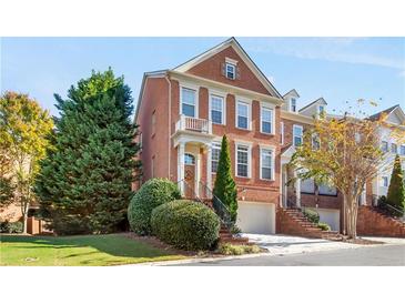 Brick three-story townhome with attached garage and manicured landscaping at 4701 Wehunt Se Trl, Smyrna, GA 30082