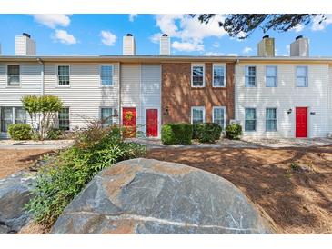 Three-unit townhouse building with red doors and landscaping at 1016 Old Holcomb Bridge Rd, Roswell, GA 30076