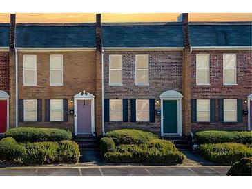 Brick townhomes featuring colorful doors, black shutters, and manicured landscaping at 245 Winding River Dr # E, Atlanta, GA 30350