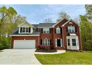Two-story brick home with attached garage and landscaped yard at 1240 Falls Creek Ct, Conyers, GA 30094