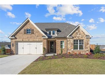 Brick house with stone accents, a three-car garage, and a landscaped yard at 2615 Yellowstone Farm Dr, Cumming, GA 30028