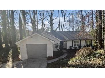 View of the home with an attached garage, surrounded by trees at 2268 Turtle Club Ne Dr, Marietta, GA 30066