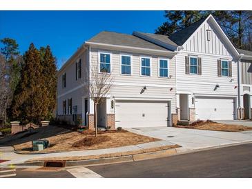 Charming townhome with two-car garage and neutral colored siding, nestled on a sunny lot with landscaped front at 754 Trevett Way, Marietta, GA 30062