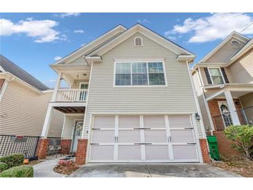 Two-story townhome with light beige vinyl siding, attached garage, and small balcony at 593 Shadow Valley Ct, Lithonia, GA 30058