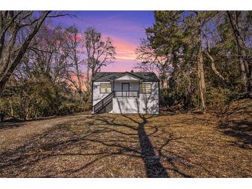 Charming exterior of a house with a porch and landscaped front yard under a beautiful sky at 1490 Broad Ne St, Conyers, GA 30012