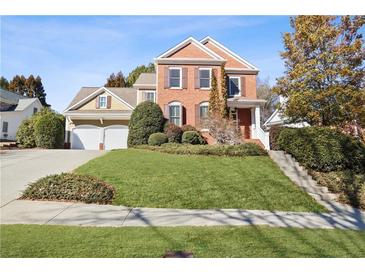 Brick and shingle two-story house with a two-car garage and landscaped lawn at 4974 Dovecote Trl, Suwanee, GA 30024