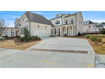 A charming two-story home with a three car garage, brick accents and manicured front yard landscaping at 11335 Bennett Ln, Johns Creek, GA 30097