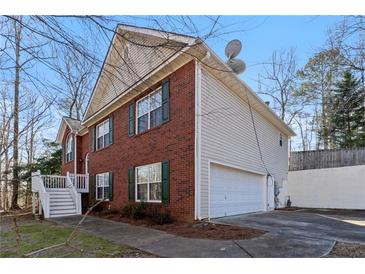 Brick and siding exterior with a two-car garage, deck and steps in a home with mature trees and well manicured landscape at 1012 Crown River Pkwy, Mcdonough, GA 30252