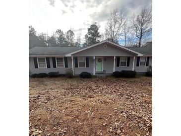 Ranch style home with gray siding, green door, and mature trees at 6540 Old White Mill Rd, Fairburn, GA 30213