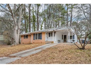 Ranch house with brick facade, driveway, and mature trees surrounding the property at 5324 Joan Of Arc Pl, Atlanta, GA 30349