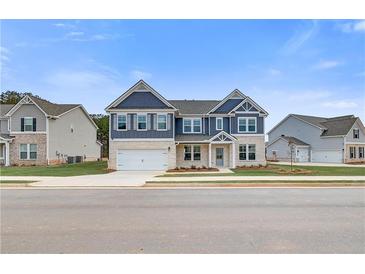 Two-story home featuring a two-car garage, stone accents, and dark blue siding under a bright blue sky at 203 Arabella Pkwy, Locust Grove, GA 30248