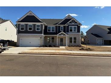 Two-story home with gray siding, brick accents, and a three-car garage at 203 Arabella Pkwy, Locust Grove, GA 30248