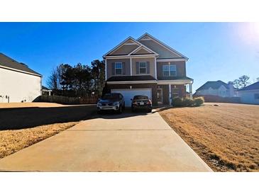 Two-story house with a brick facade and a two-car garage, parked cars in driveway at 100 Canyons Ct, Hampton, GA 30228