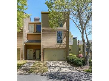 Tan two-story townhome with attached garage and landscaping at 1107 Riverbend Club Se Dr, Atlanta, GA 30339