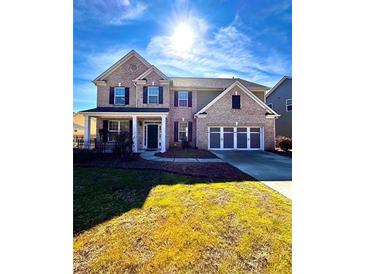 Brick two-story house with a three-car garage and landscaped lawn at 3026 Bridge Walk Dr, Lawrenceville, GA 30044