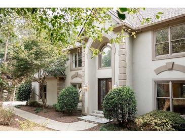 Two-story house with light beige siding, arched entryway, and landscaping at 255 Grogans Lake Pt, Atlanta, GA 30350