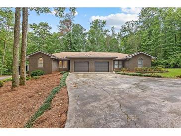 Brick ranch home with mature landscaping, two-car garage, and circular driveway surrounded by shade trees at 263 Weldon Rd, Palmetto, GA 30268