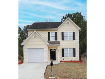 Charming two-story home with light yellow siding, black shutters, and well-maintained front yard at 7015 Setters Way, Lithonia, GA 30038