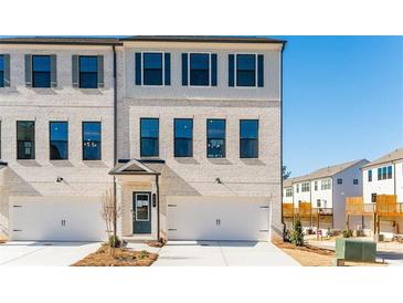 Charming white brick townhome featuring blue shutters, a front-entry two-car garage, and tasteful landscaping at 320 Oldvine Dr, Lawrenceville, GA 30044