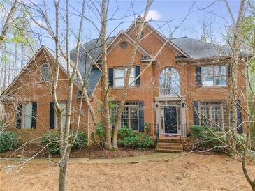 Charming brick two-story home with mature landscaping, arched window, and dark shutters at 785 Charleston Dr, Roswell, GA 30075