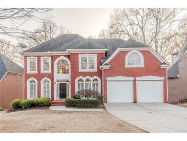 Stately brick home featuring a two-car garage, arched windows, and a meticulously landscaped front yard at 3184 Islesworth Trce, Duluth, GA 30097