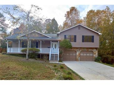 Two-story house with brown siding, white porch, and attached two-car garage at 1129 Gate Post Ln, Lawrenceville, GA 30044
