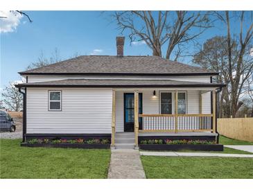 Charming white cottage with a black trim, landscaped yard, and a porch at 1617 Church Ne St, Conyers, GA 30012