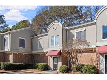 Brick townhouse with gray siding, red awning, and landscaping at 3301 Henderson Mill Rd # A2, Atlanta, GA 30341
