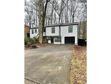 Two-story house with white siding, black accents, and a paved driveway at 7035 Stone Wood Nw Dr, Kennesaw, GA 30152