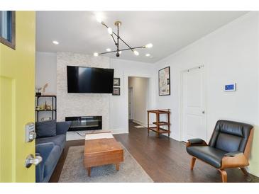 Bright living room features a modern fireplace with stone surround, hardwood floors, and stylish light fixture at 1018 Westmont Sw Rd, Atlanta, GA 30311