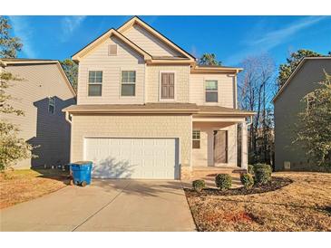 Two-story house with beige siding, white garage door, and landscaping at 157 Parkview Place Dr, Mcdonough, GA 30253