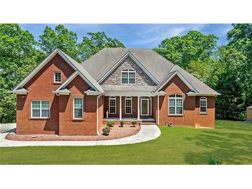 Beautiful brick home featuring a well-manicured lawn and a charming covered front porch entrance at 6020 Cochran Mill Rd, Chattahoochee Hills, GA 30268