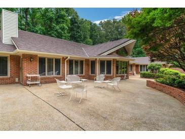 A spacious concrete patio is furnished with tables and chairs overlooking the meticulously landscaped yard at 3781 Anneewakee Rd, Douglasville, GA 30135