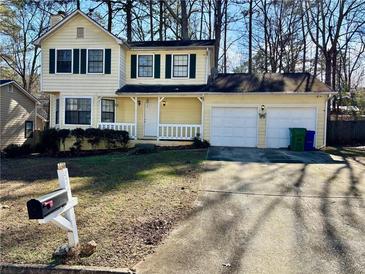 Two-story yellow house with a white garage and landscaped yard at 5615 Pennybrook Ct, Stone Mountain, GA 30087