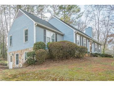 Ranch style home with light blue siding, stone accents, and mature landscaping at 118 Knotts Landing Dr, Woodstock, GA 30188