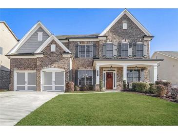 Brick two-story home with a three-car garage and manicured lawn at 4200 Oxcliffe Grv, Suwanee, GA 30024